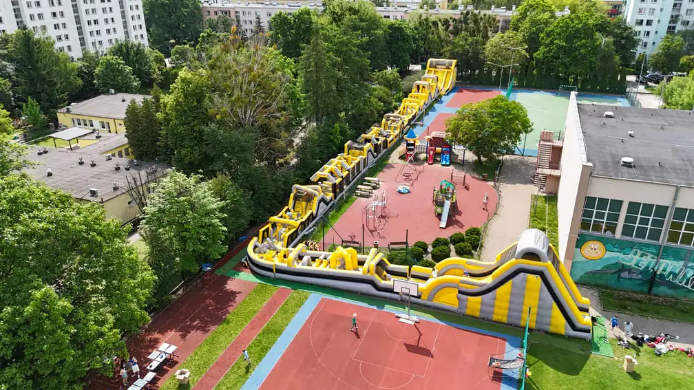 Dmuchany tor przeszkód na wyjeździe integracyjnym — uczestnicy pokonują tor podczas team buildingu